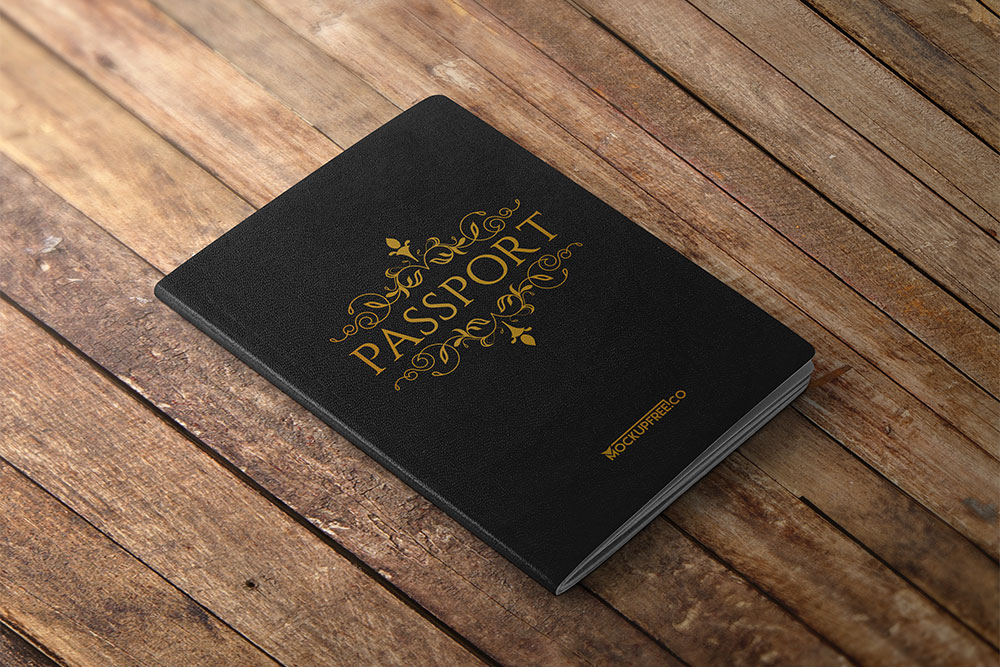 A black passport book mockup with golden ornate details lies on a textured wooden surface, symbolizing travel and exploration.