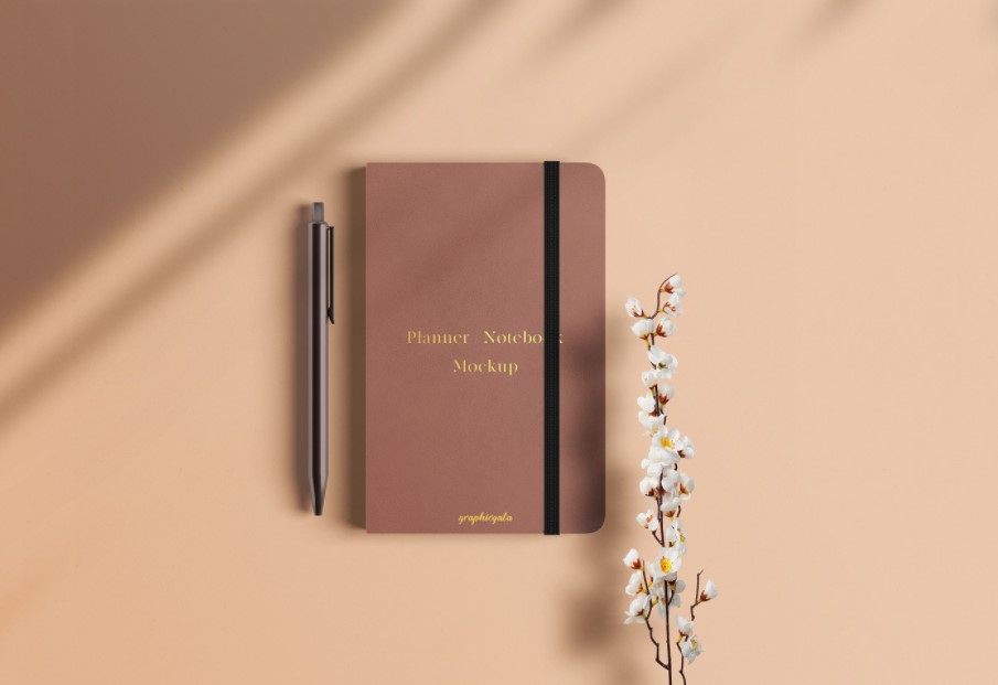 Maqueta de cuaderno con bolígrafo y flor