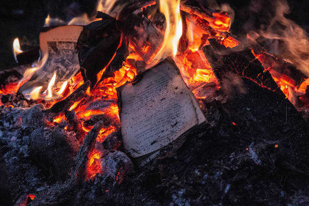 Book pages consumed by flames in a fiery blaze, the written word turning to ash and embers.