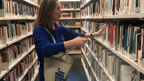 Una mujer recibiendo libros de la biblioteca