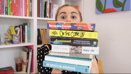 Chica sosteniendo libros apilados