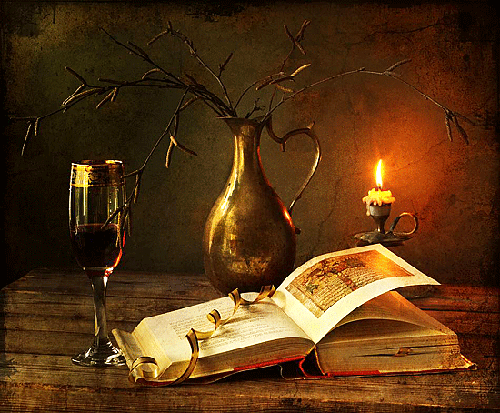 Libro antiguo con una copa de vino, vela y árbol seco sobre una mesa