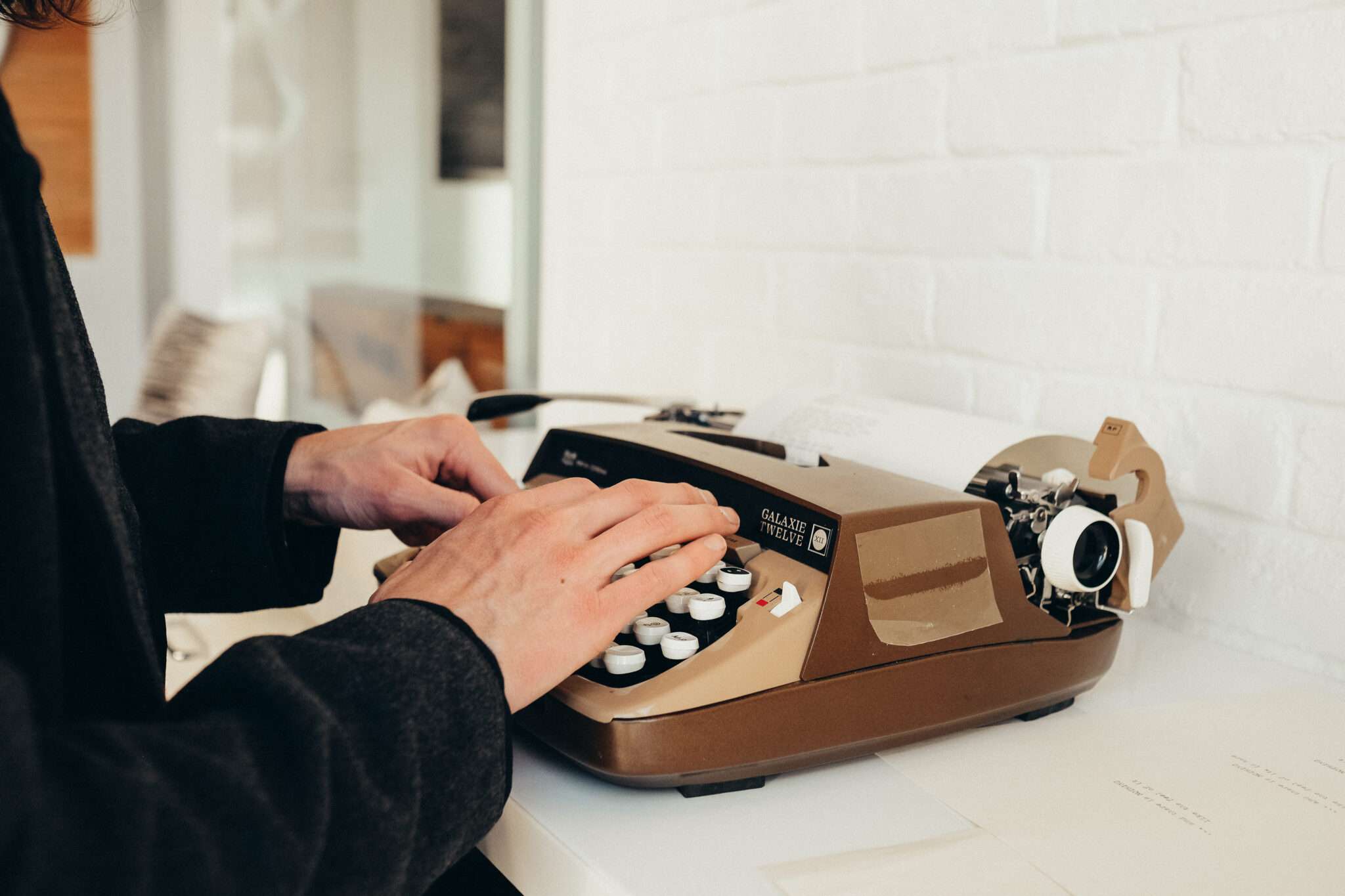 A person typing on a vintage typewriter, evoking a sense of nostalgia for classic writing tools.